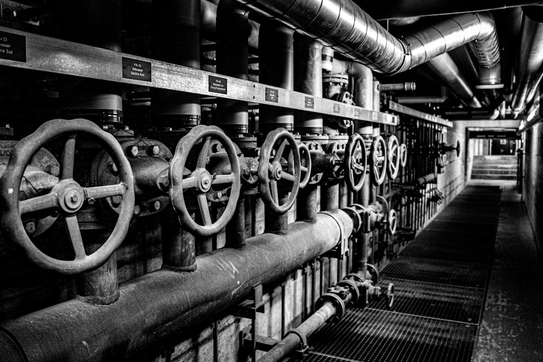 Cold War machinery inside the Sonnenberg bunker in Lucerne, Switzerland. Black and white photo of large industrial valves and pipes controlling water and air systems in one of the world’s biggest civil defense shelters.